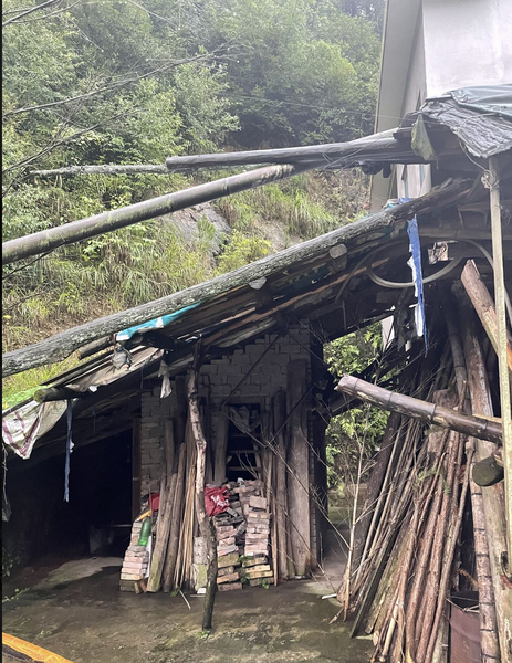 房屋正东侧：竹竿和木板搭成的破旧棚屋，屋顶歪斜，里面堆着砖块和杂物，这里是厕所所在
