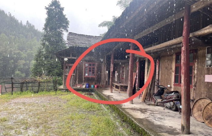 雨中的院落：两栋木结构房屋在拐角处连成一体，红圈圈出两屋相接的门廊位置，院前是草地，廊下停着摩托车