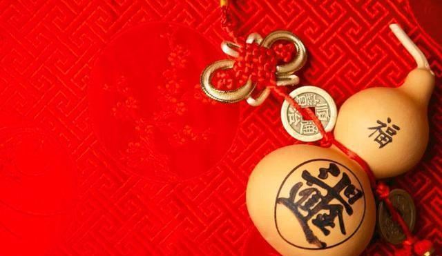 红色锦缎上摆着两只葫芦，一只写有福字，另一只写着篆体大字，旁边系着红色中国结和一枚铜钱